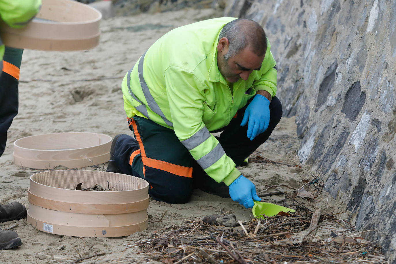 Operarios retiran los pellets o bolitas para fabricar plástico que aparecen en las playas de Asturias, tras la caída de un contenedor de un barco el pasado diciembre, esta mañana en la playa asturiana del Aguilar.