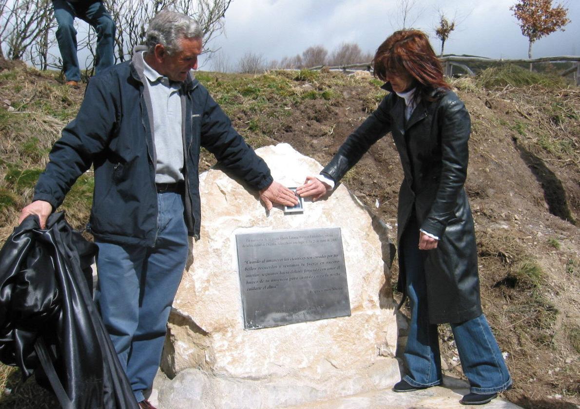 Los padres de Sheila Barrero, junto a la placa y la foto de su hija que se levanta en su memoria en el lugar en el que la mataron, en el Alto de La Collada.