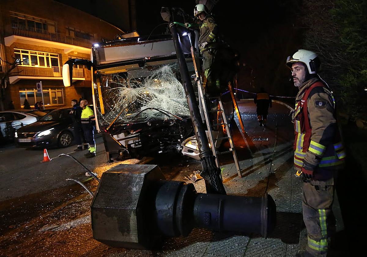 El autobús accidentado, montado sobre la acera contra la farola.