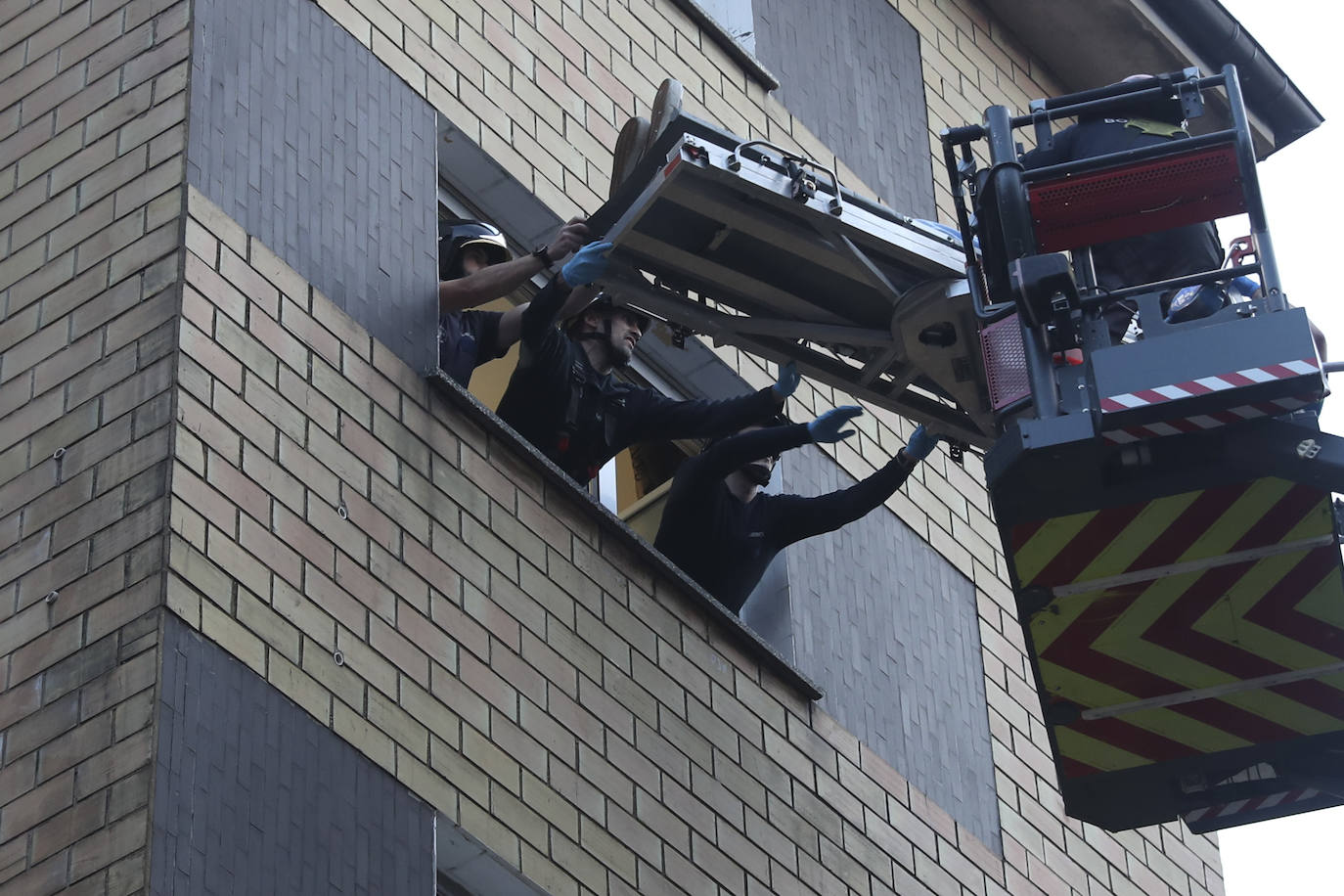 Maniobra de los bomberos de Gijón para sacar a una mujer inconsciente por la ventana