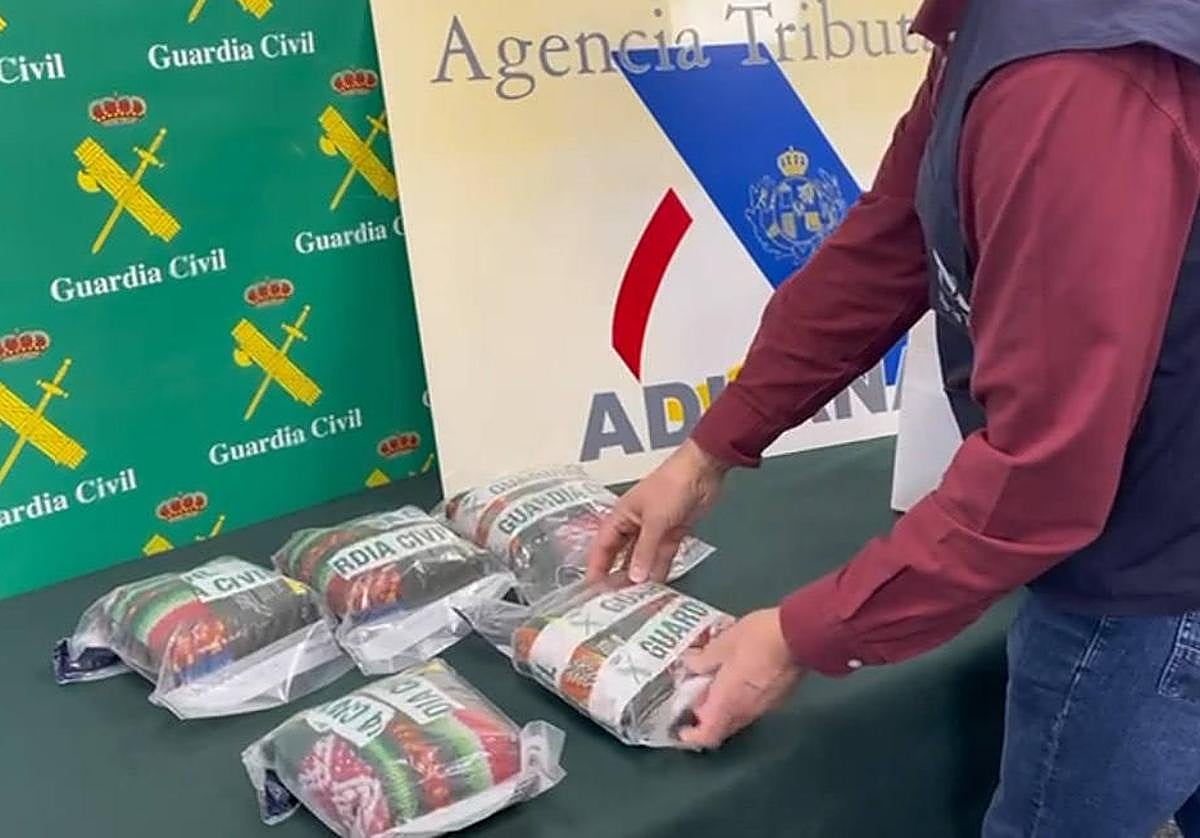 Un agente saca de una bolsa los paquetes intervenidos con polvo de hoja de coca.