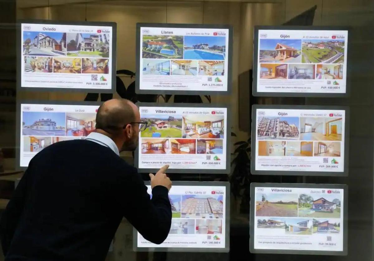 Un hombre observa con atención los anuncios en el escaparate de una agencia inmobiliaria.