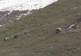 Sanitarios atienden a uno de los heridos junto dos vehículos que bajaron desde la pista para ayudar. El coche accidentado no está a la vista.