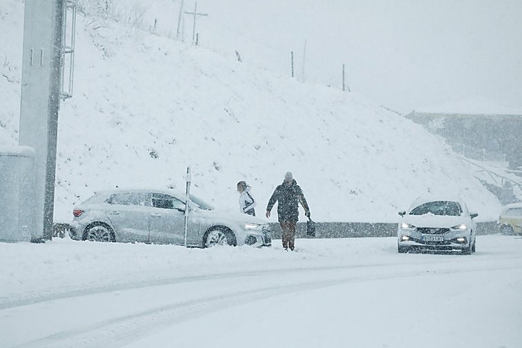 Un hombre, con una pala en la mano, se dirige hacia su coche en la carretera de Pajares para tratar de quitar la nieve acumulada que le impedía mover el vehículo.