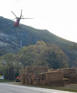 El helicóptero, cargando la paja para lanzarla en los montes de Caso que se quemaron en 2023.