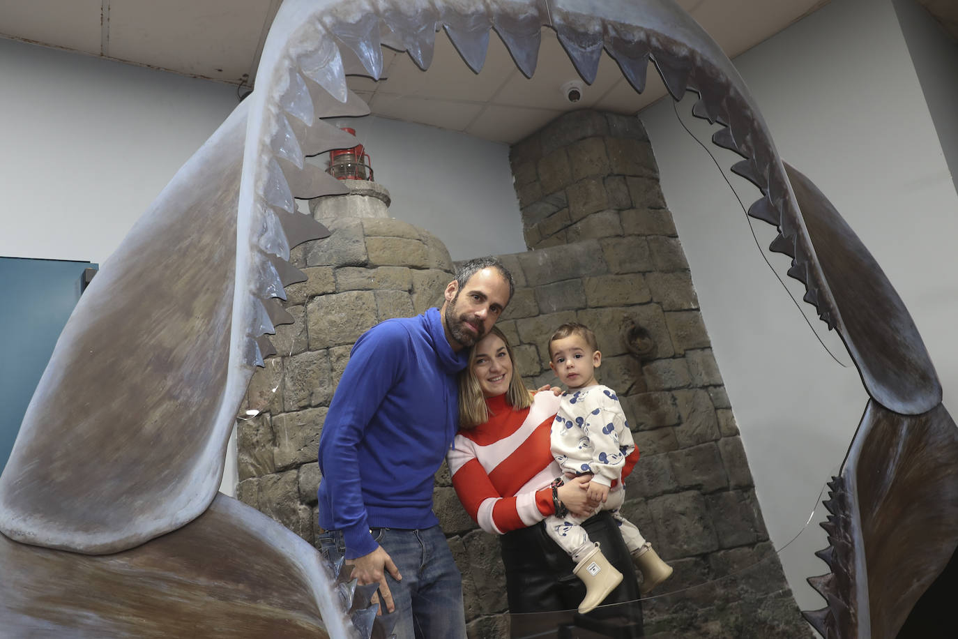 Una familia posa tras una de las piezas que conforma la exposición 'Tiburones'.