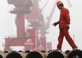 Un trabajador camina sobre tubos de acero en el puerto de Lianyungang.