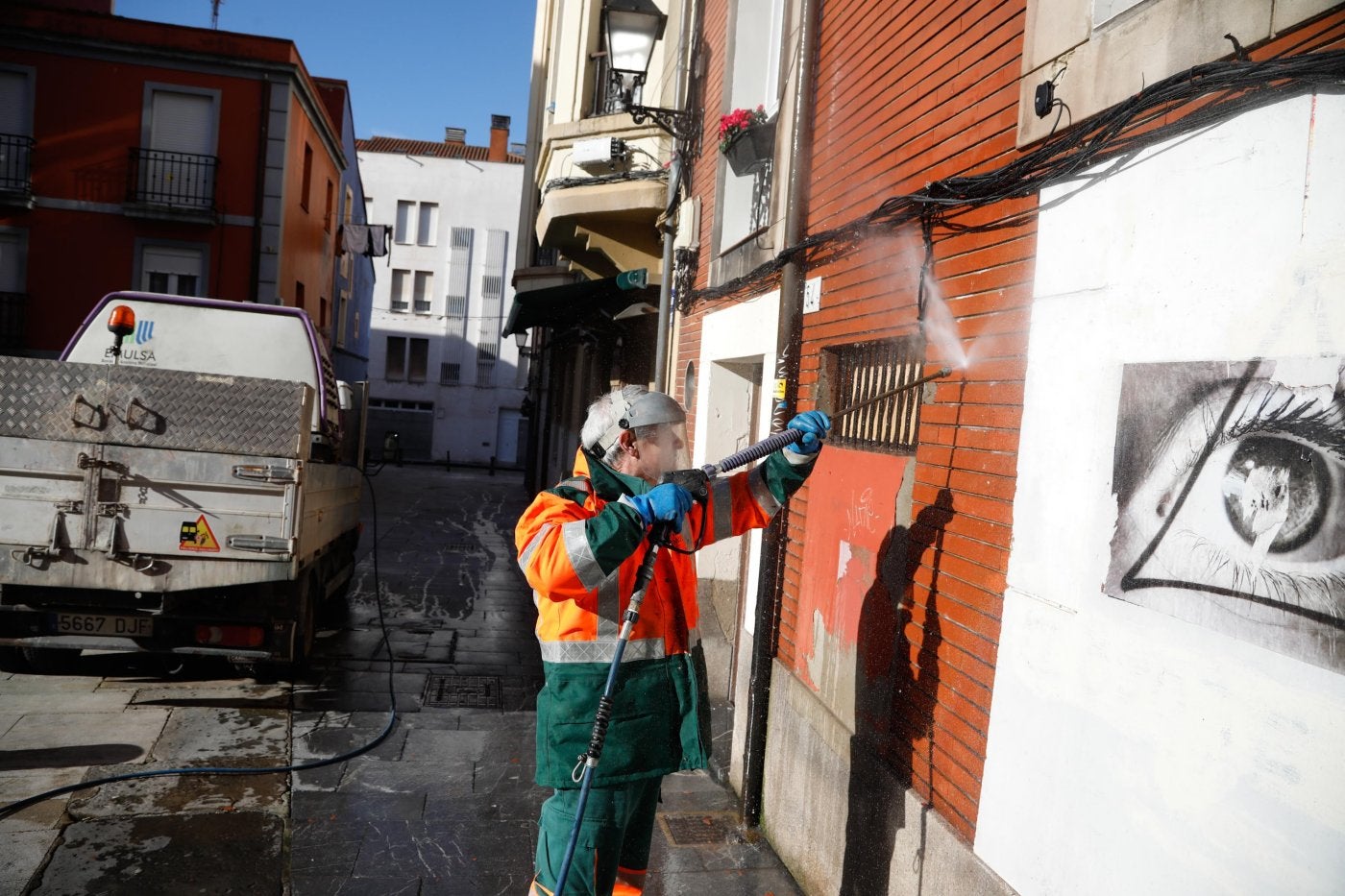 Trabajadores de Emulsa quitan las pintadas de una fachada de la calle Rosario.