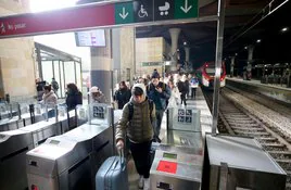 Usuarios del tren de la línea Gijón-Madrid salen del andén tras llegar el tren a Oviedo.
