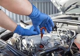Un mecánico comprueba el aceite de un coche.
