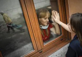 Laura García, técnico superior de imagen diagnóstica del HUCA, saluda a su hija desde el interior de la habitación donde está aislada en su casa de Moreda, en una fotografía tomada en los meses de lo peor de la pandemia.