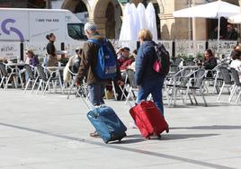 Dos turistas caminan por la plaza de España para dirigirse al Hotel Palacio de Avilés.