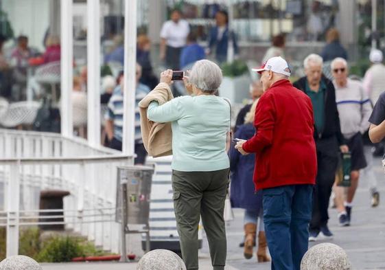 Una pareja de jubilados toma una fotografía en Gijón.