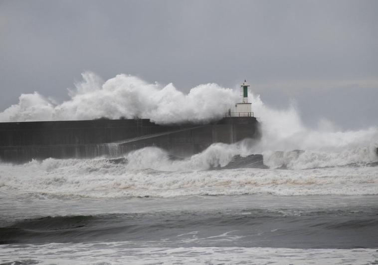 El faro de la barra de San Esteban, ayer, batido por las olas, con la rampa por la que subió el ciudadano inglés antes de ser arrastrado.