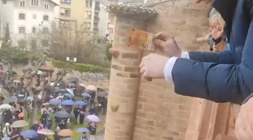 Diego Bengoa a punto de lanzar un billete de 50 euros a la multitud congregada en la plaza de la iglesia.