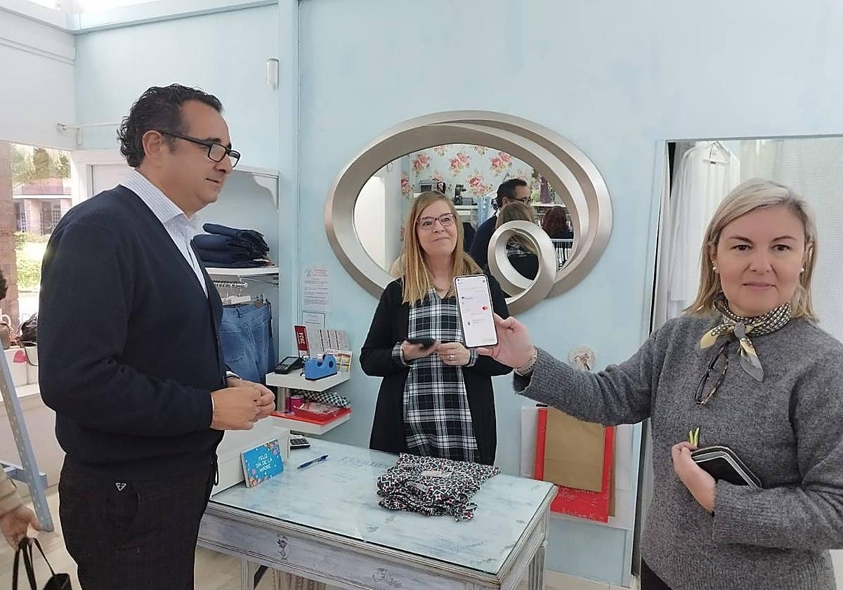 De izquierda a derecha, el director general de Comercio, Julio González Zapico, y la propietaria de la tiendina de Nu en Langreo, Nuria Álvarez, con una clienta que ya había descargado los bonos descuento en su teléfono móvil.