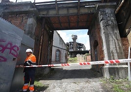 Un operario de la empresa Hercal, ayer al mediodía, en la Fábrica de Gas junto a la nave de la Popular Ovetense. La entrada por la calle Paraíso con los carteles de obra.