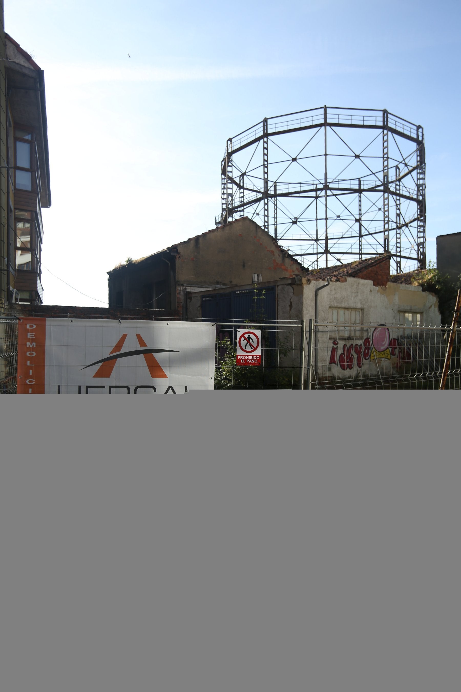 El cartel de Hercal, la empresa que acomete los derribos, con el gasómetro de fondo.