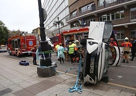 En primer término, el estado en el que quedó el coche siniestrado. Detrás del vehículo, bomberos, policía y sanitarios en el lugar del accidente.