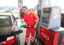 Un trabajador de una estación de servicio carga el depósito de un vehículo.