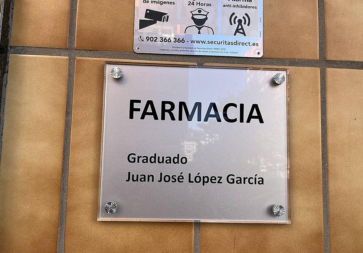 Imagen secundaria 1 - Farmacia en la que trabajaba el fallecido y flores depositadas en la puerta del negocio.