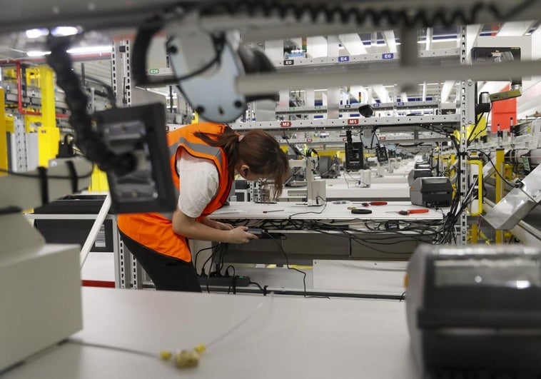 Una trabajadora ultima los preparativos de uno de los puestos de trabajo del súper centro logístico de Amazon en el polígono de Bobes, en Siero.