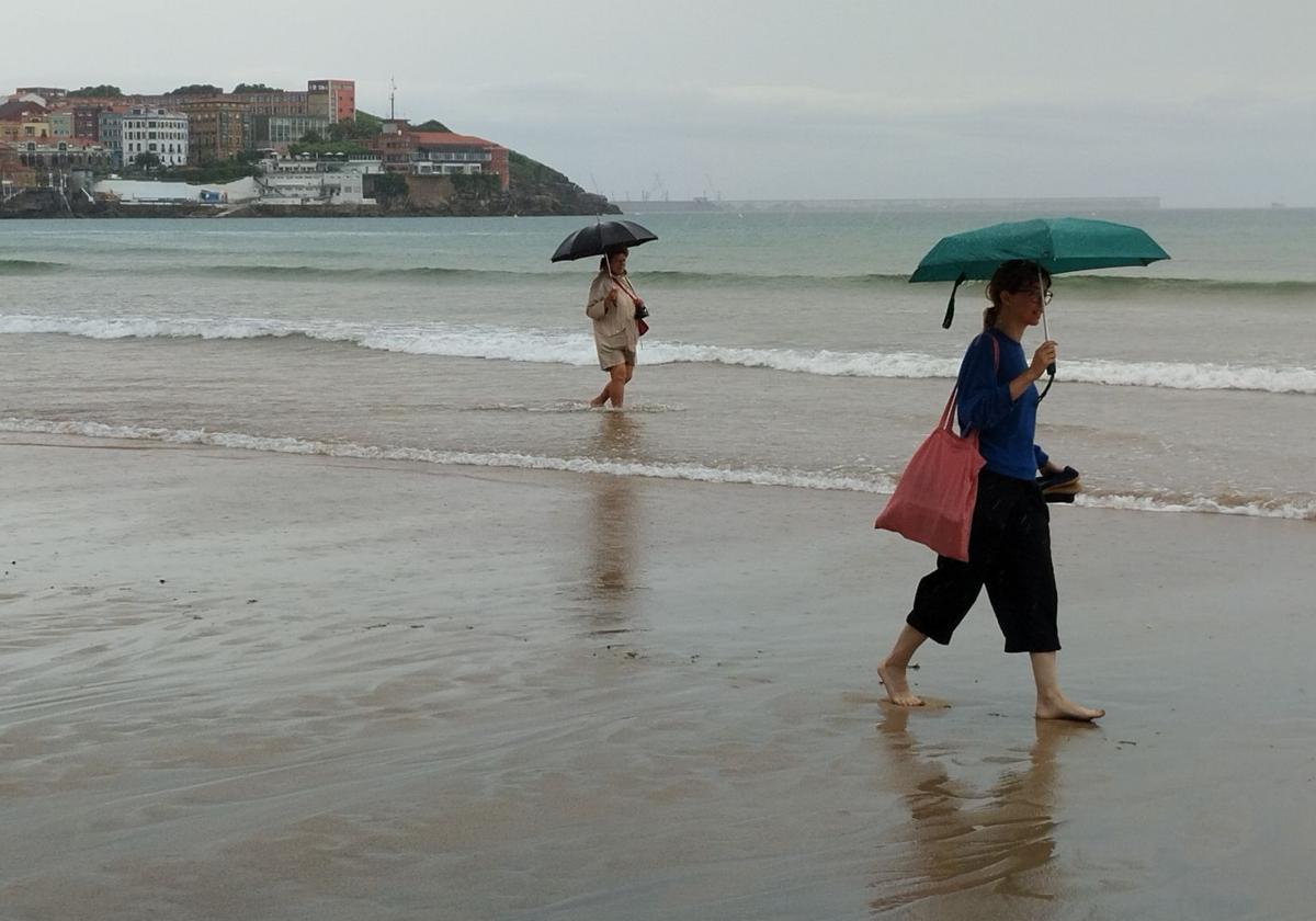 Dos mujeres pasean este martes por la playa de San Lorenzo de Gijón.