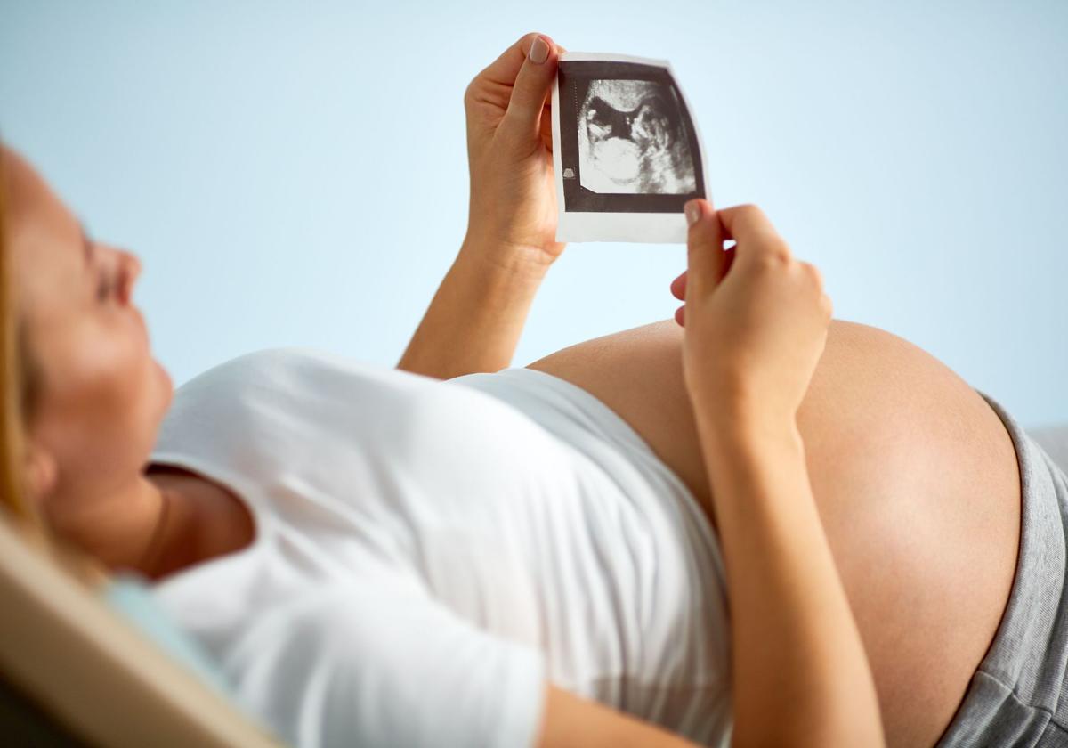 Una mujer embarazada observa una ecografía de su bebé.