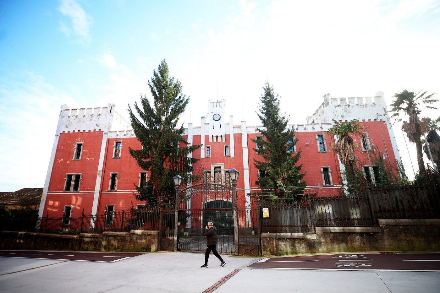 Un hombre pasa por delante del castillo de entrada a la fábrica de armas de La Vega, junto al nuevo tramo de carril bici.