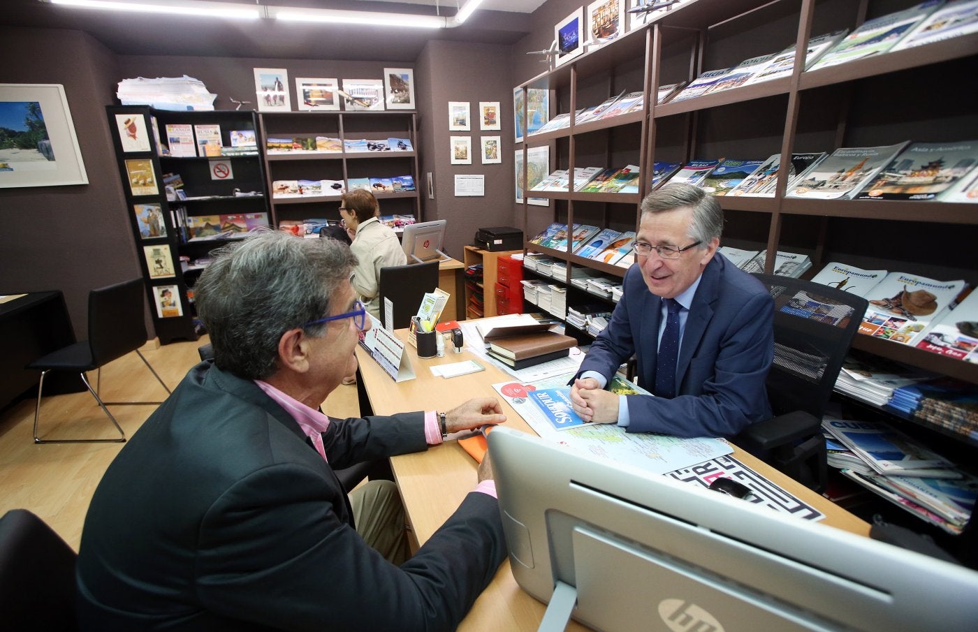 Íñigo Fernández, en su agencia de viajes, atiende a un cliente que le consulta por un viaje vacacional.