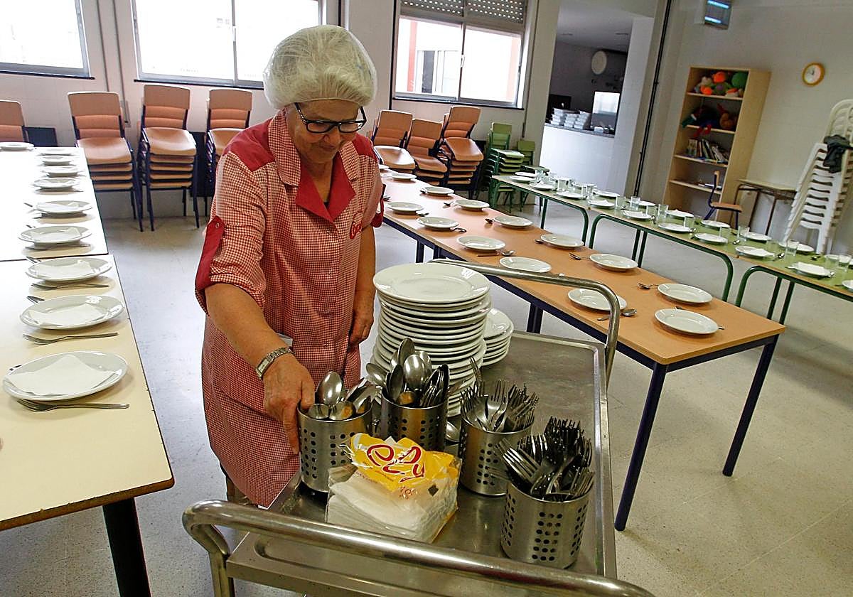 Una trabajadora prepara las mesas del comedor.