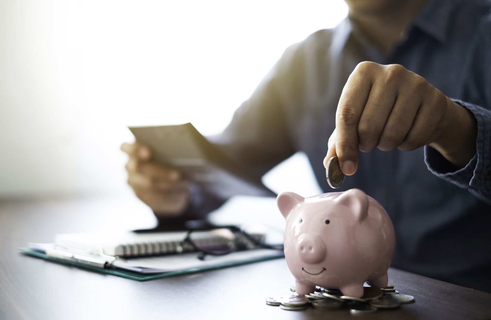 Un hombre mete dinero en una hucha.