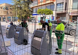 Unos operarios colocan unos contenedores de reciclaje.
