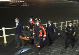 Bomberos y servicios funerarios trasladan el cadáver del joven ahogado en la playa de San Lorenzo, el 24 de junio de 2020.