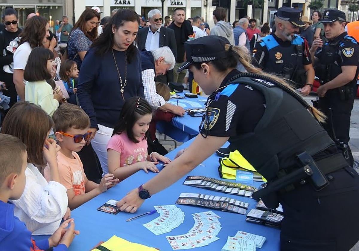 Los niños cubren los carnés que les acredita como policías locales infantiles.Un miembro de Protección Civil enseña a dos pequeños a realizar una reanimacióncardiopulmonar.
