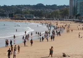 Animación en el arenal gijonés ayer a las dos de la tarde, con paseantes, bañistas y surfistas.