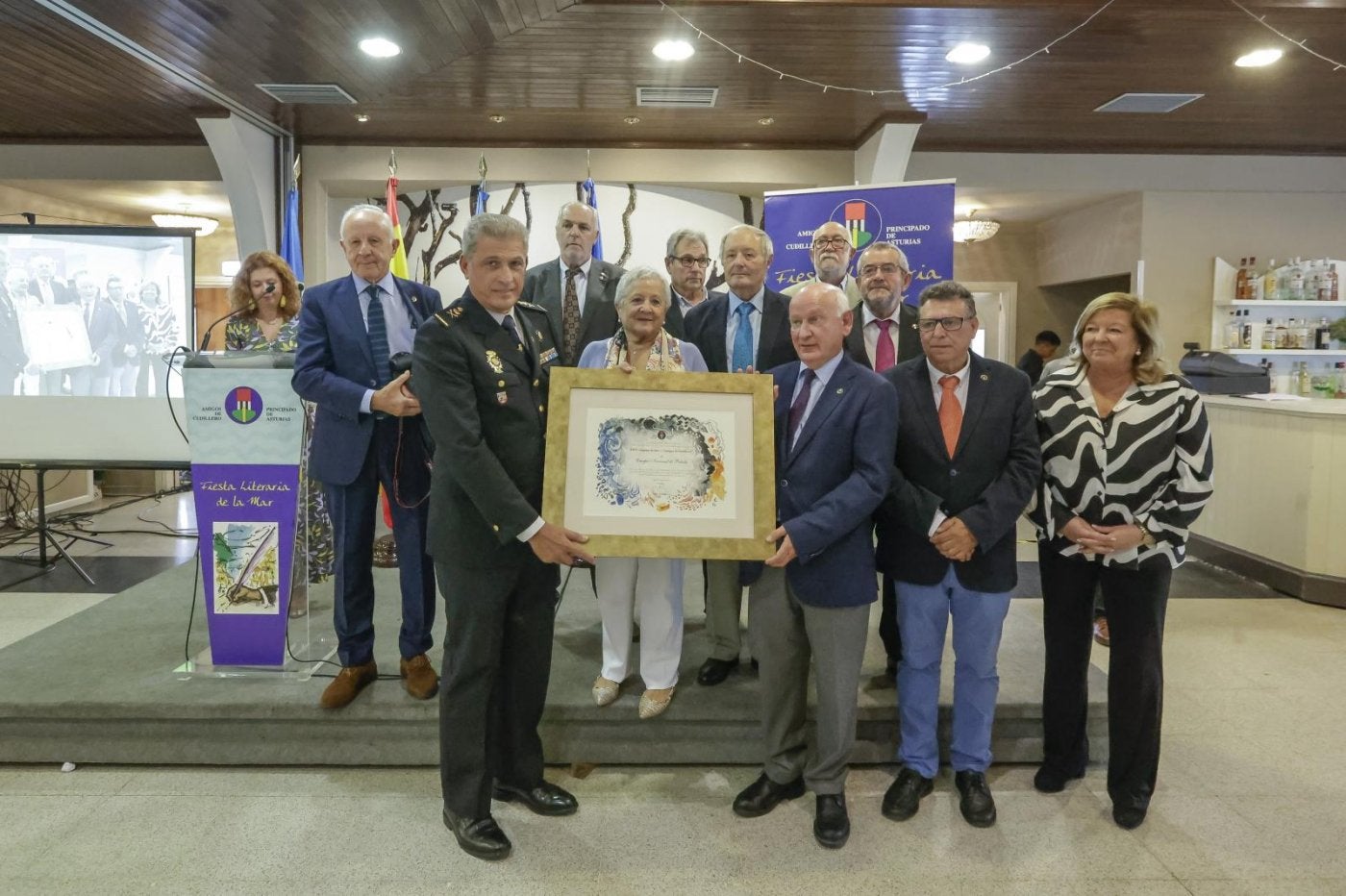 El jefe superior de Policía sostiene el diploma de la Asociación 'Amigos de Cudillero', junto a su presidente y el resto de la directiva.