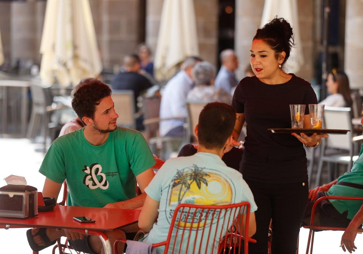 Una camarera atiende a unos clientes en la terraza de un local de hostelería.