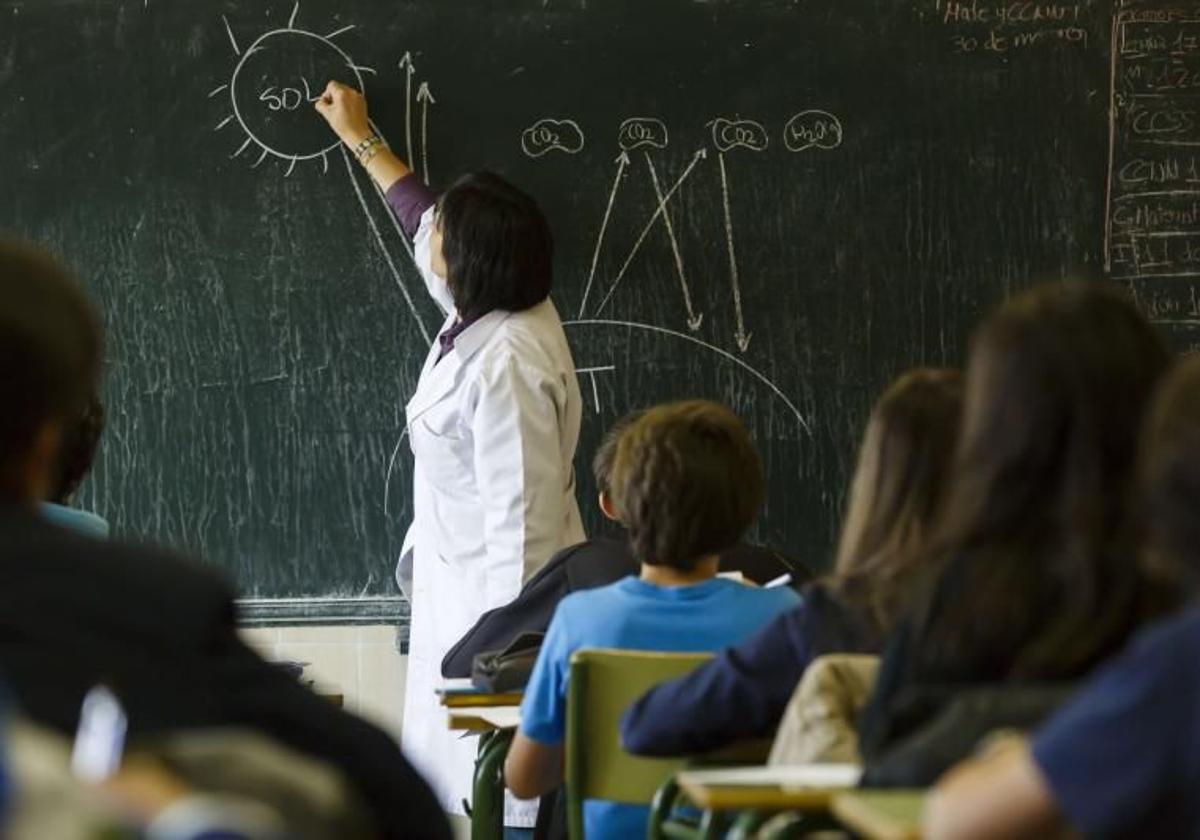 Una profesora escribe en la pizarra.