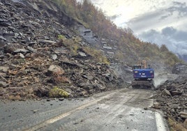 Un operario trata de despejar la carretera en la zona argayada.