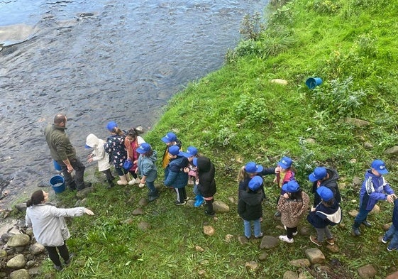 Un grupo de escolares, mientras esperaban su turno para coger los alevines de trucha y lanzarlos a las aguas del río Nalón.