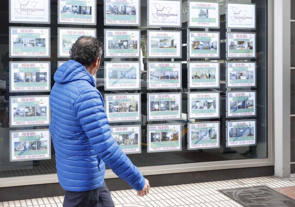 Un hombre camina frente a una inmobiliaria.