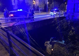 El vehículo, volcado en el fondo del río San Juan en Mieres, se llevó por delante las barandillas.