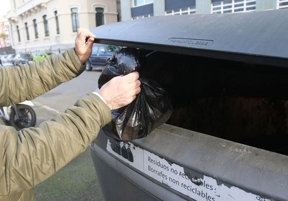 Un vecino tira la basura en un contenedor para residuos generales, de los que el 90% podría separarse para el reciclaje o reutilización.