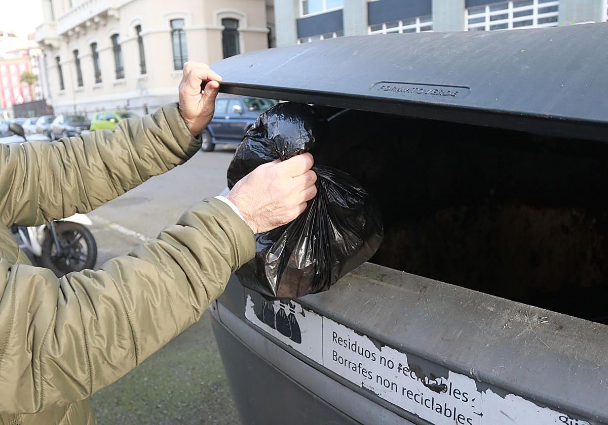 Un vecino tira la basura en un contenedor para residuos generales, de los que el 90% podría separarse para el reciclaje o reutilización.
