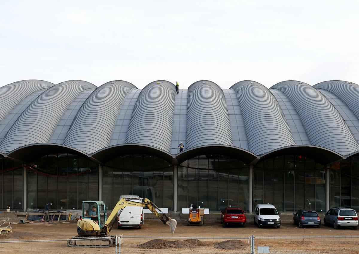 Imagen secundaria 1 - Arriba, la comitiva municipal en la pista multiusos del Palacio de los Deportes de Oviedo; a la izquierda, la zona exterior del edificio, aún en obras; y a la derecha, Alfredo Canteli (centro) junto al resto de asistentes a la visita.