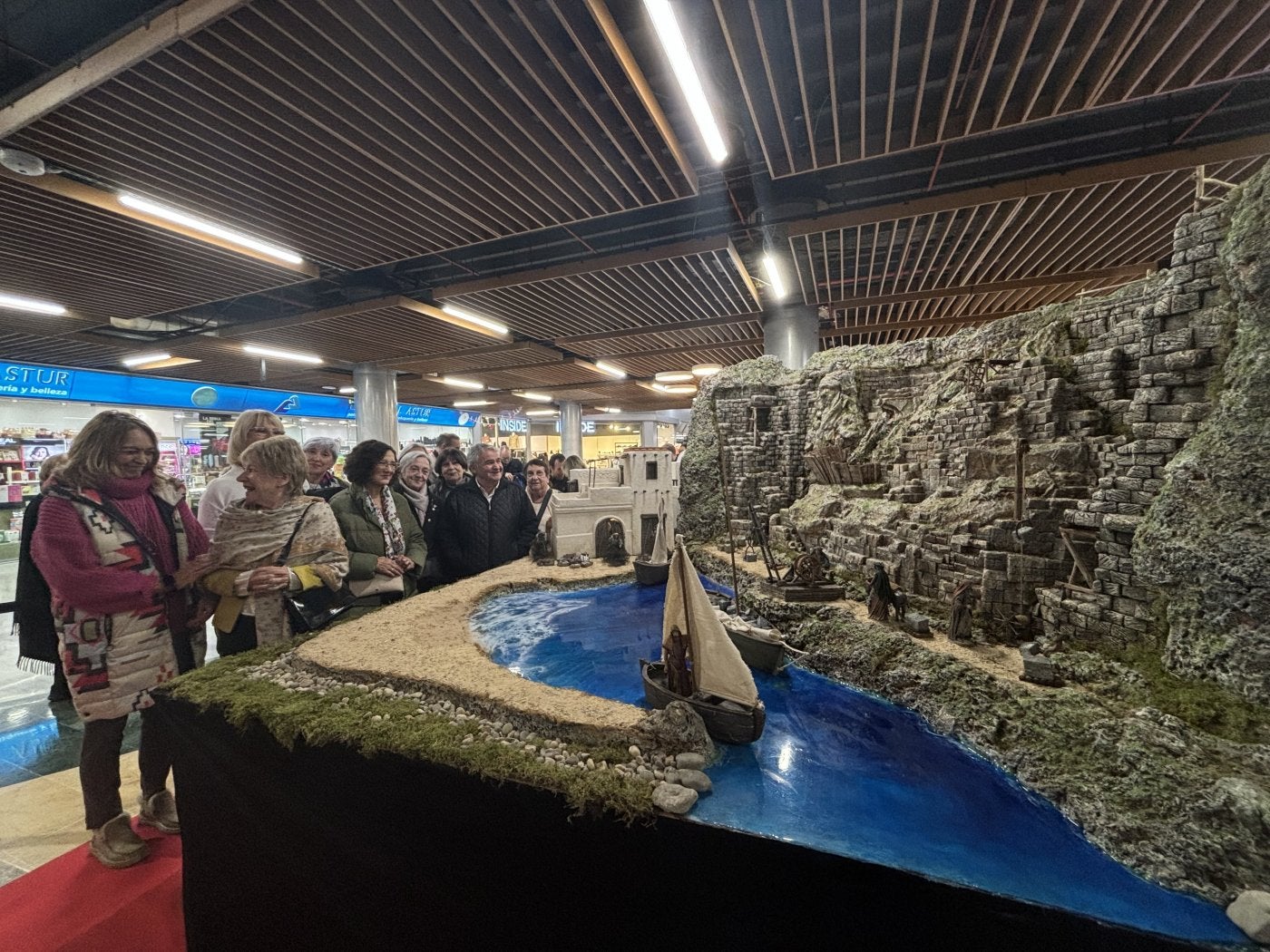 Mari Paz Álvarez, gerente de Los Fresnos, y Plácida Novoa, presidenta de la Asociación Belenista, junto a otros miembros de la entidad, frente al belén de 'Los pescadores'.