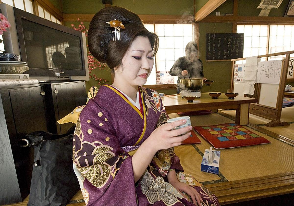 Una joven japonesa celebra su mayoría de edad su primer sorbo legal de sake.