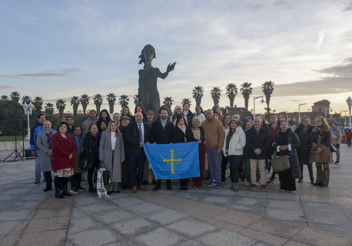 Álvaro Queipo, presidente del PP de Asturias, Guzmán Pendás y Rosa Tania Vela con la bandera de Asturias, rodeado de los participantes en el homenaje a los emigrantes.