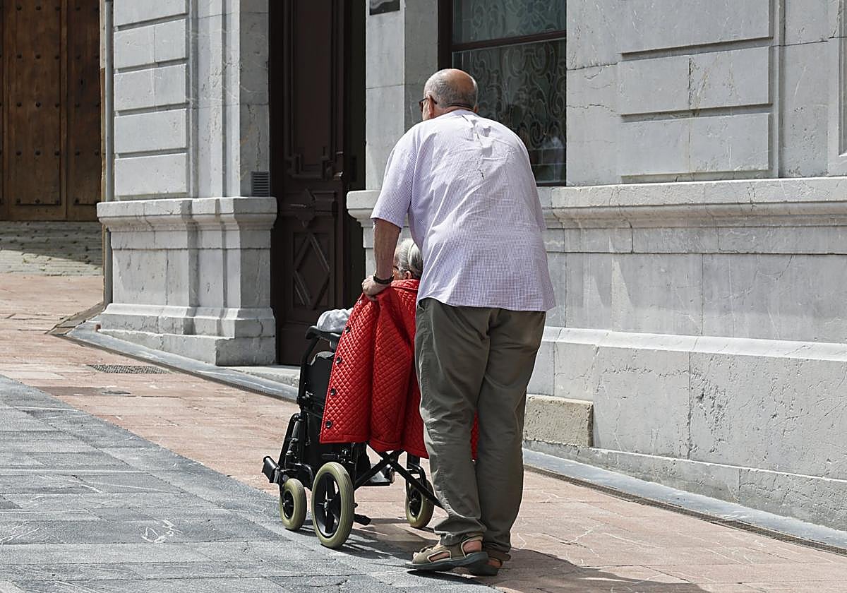 Un hombre pasea a una persona dependiente.